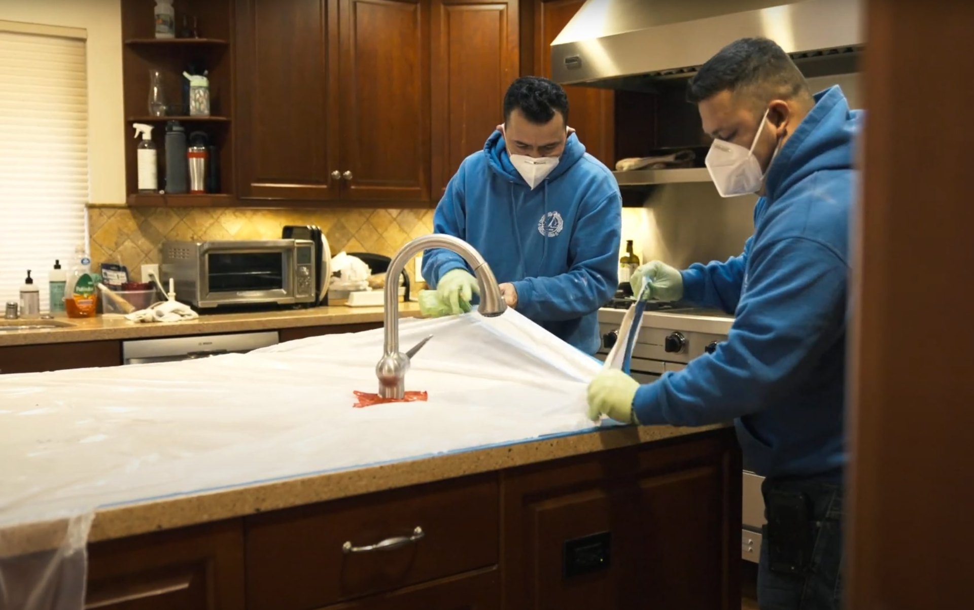Water damage restoration professionals working in modern kitchen Professional water damage restoration technicians cleaning and sanitizing kitchen surfaces after water damage